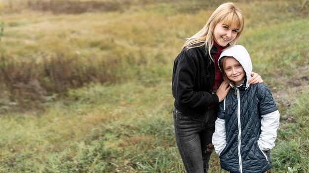 Blonde mother and little girl posing in nature