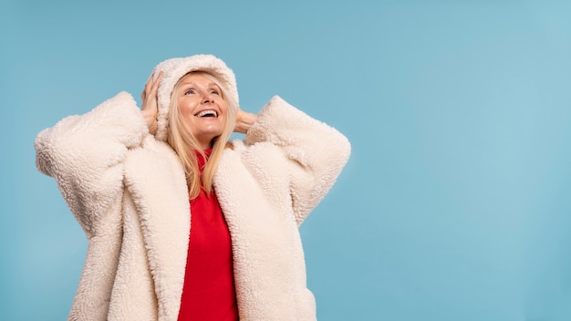 Foto gratuita donna senior bionda che è felice e sorridente contro una priorità bassa blu