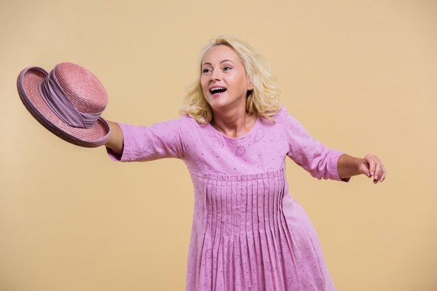 Blonde senior woman holding a pink hat