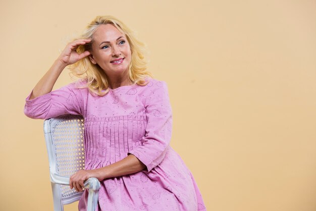 Blonde senior woman wearing a pink dress with copy space