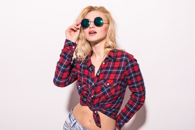 Blonde in short red checkered t-shirt black round sunglasses isolated on pink