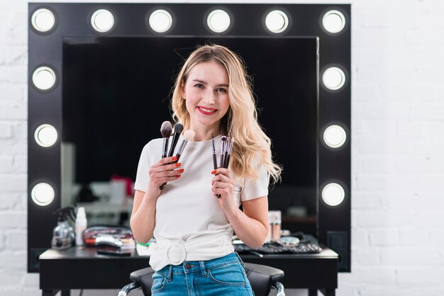 Blonde showing brushes for makeup in salon