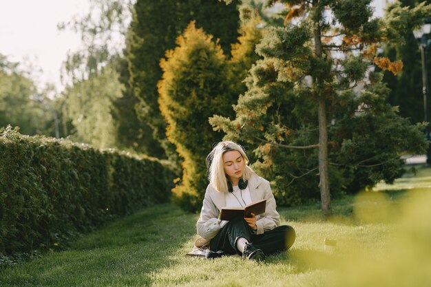Блондинка сидит на траве с наушниками