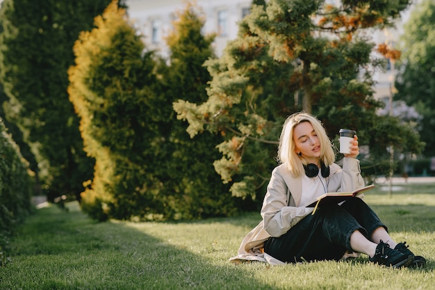 Free photo blonde sitting on a grass with headphones