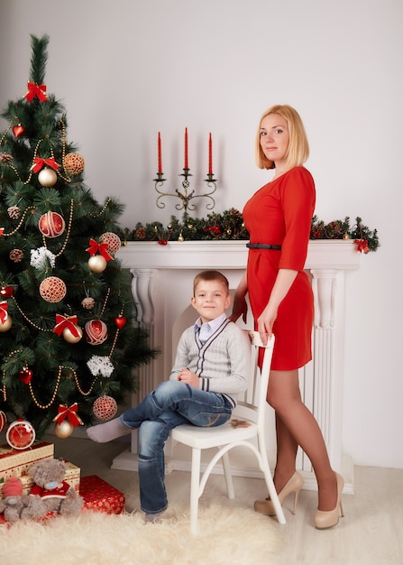 Free photo blonde standing woman and her son in a chair