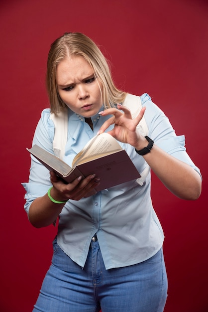 Blonde student woman holds her books and looks terrified.
