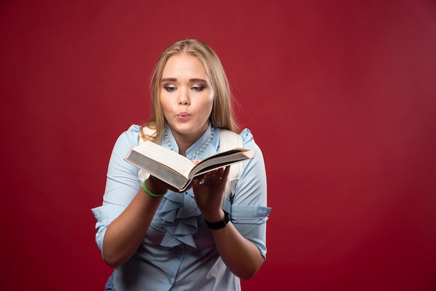 Blonde student woman holds her books and looks terrified.