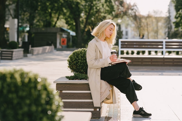 Blonde in a summer city with cup of coffee