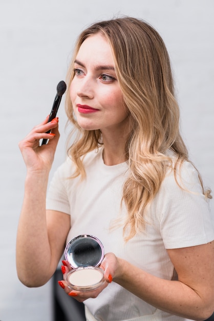 Blonde with powder applying makeup with brush