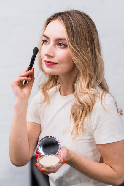 Blonde with powder applying makeup with brush