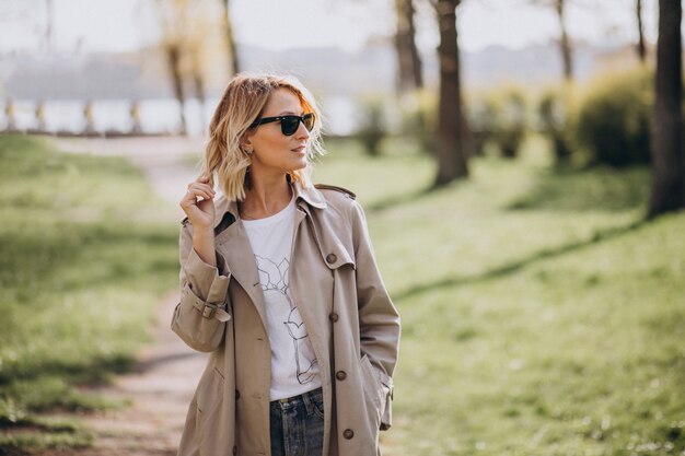 Blonde woman in coat outside in park