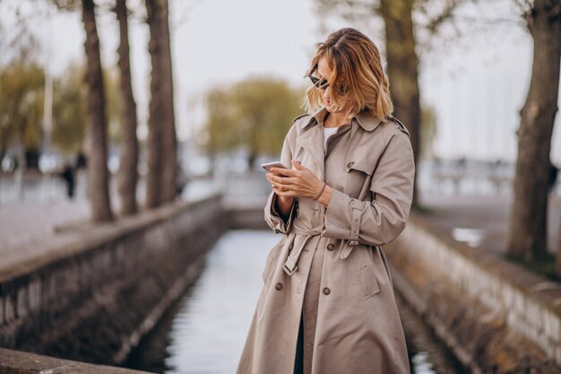 Blonde woman in coat outside in park