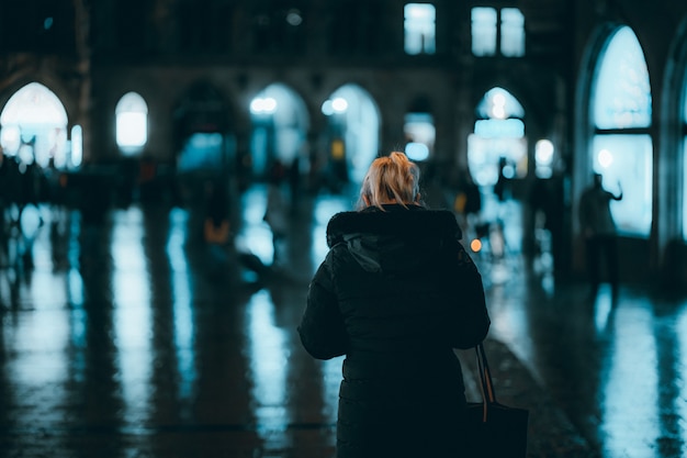 Blonde woman in a coat standing in the street at night