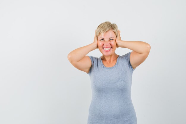 Blonde woman covering her ears with her hands and smiling