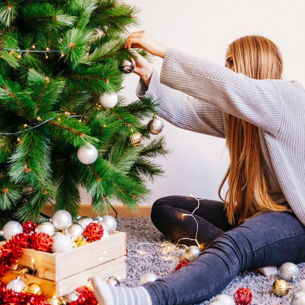 クリスマスツリーを飾るブロンドの女性