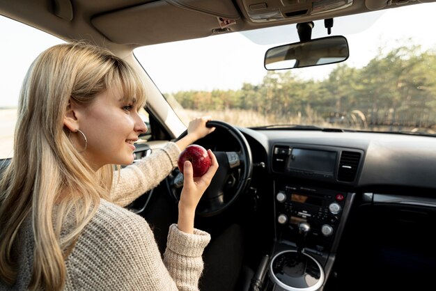 Blonde woman driving and eating a delicious apple