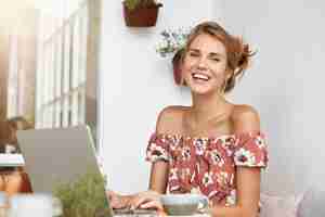 Free photo blonde woman in floral dress in cafe