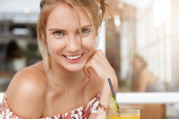 Blonde woman in floral dress in cafe