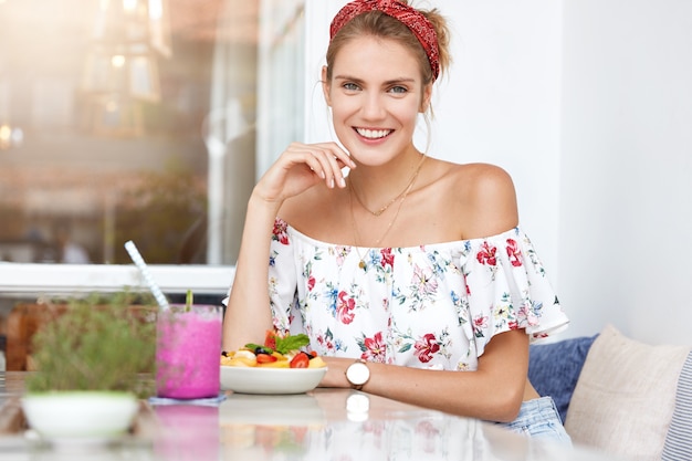 Blonde woman in floral dress in cafe