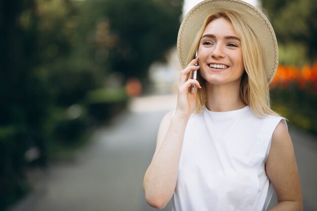 Blonde woman in hat using phone