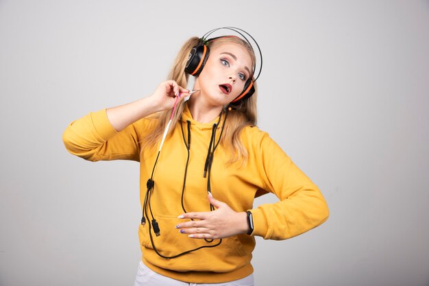 Blonde woman in headphones holding her stomach.