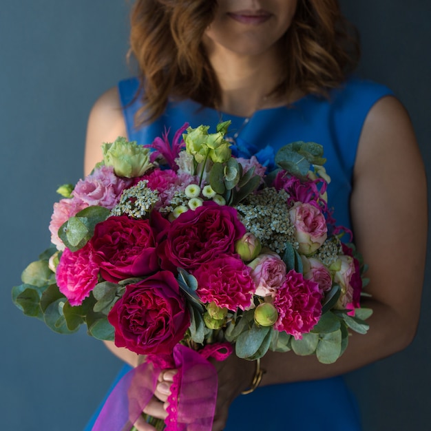 Blonde woman holding a bouquet of peonies.