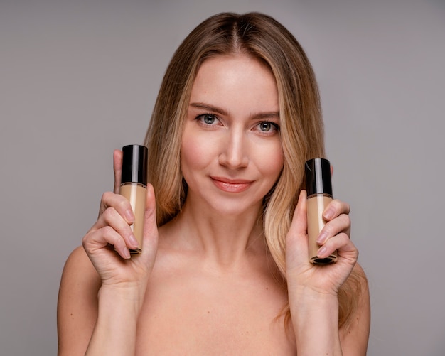 Blonde woman holding a foundation bottles