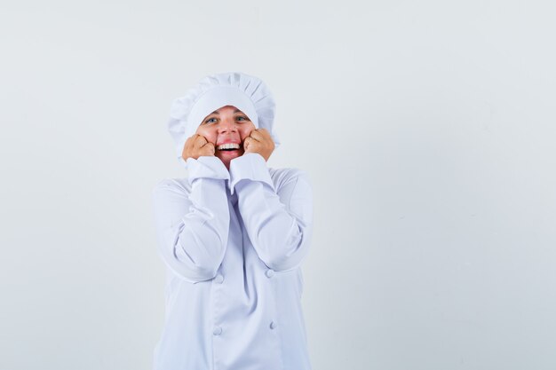 금발의여자가 턱에 손을 잡고 흰색 요리사 유니폼에 주먹을 떨림 하 고 예쁜 찾고.