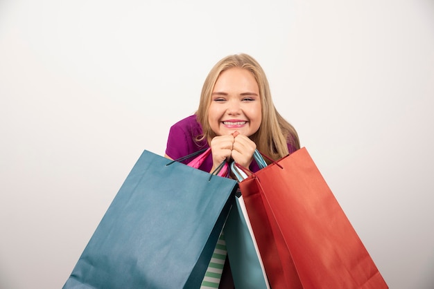 Blonde woman holding shopping bags with happy expression.