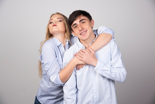 Blonde woman hugging brunette guy model on gray background