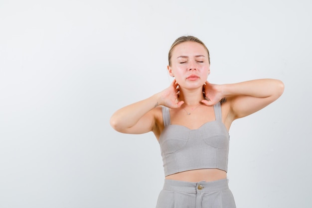 The blonde woman is dreaming by holding her hands behind neck  on white bakcground