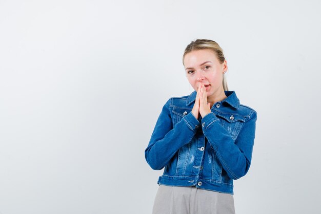 The blonde woman is holding her hands on mouth on white background