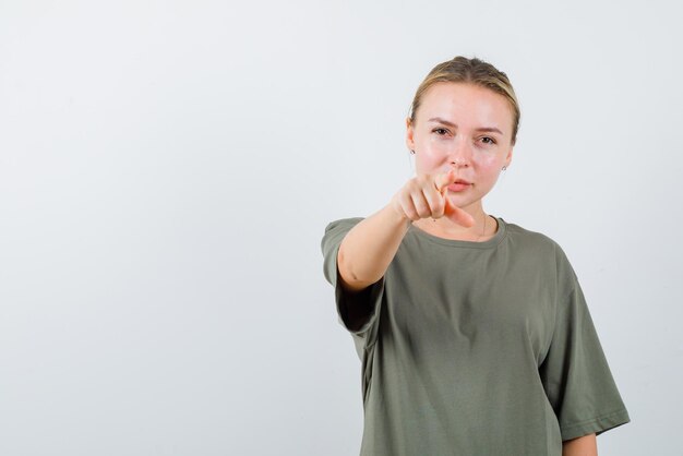 The blonde woman is pointing to camera with her forefinger on white background