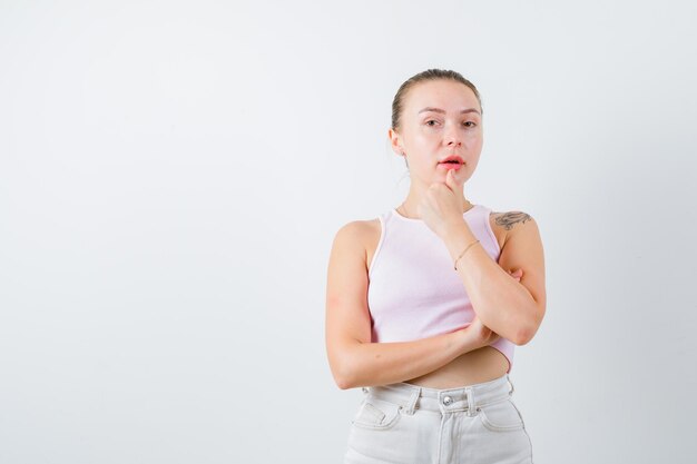 ブロンドの女性は白い背景の上のカメラのポーズをとっています