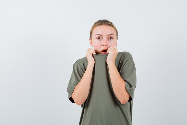 The blonde woman is pulling up her collar on white background