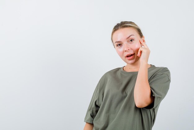 The blonde woman is putting her forefinger on temple on white background