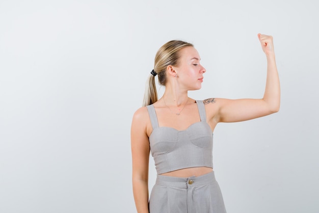 The blonde woman is showing her muscle on white background