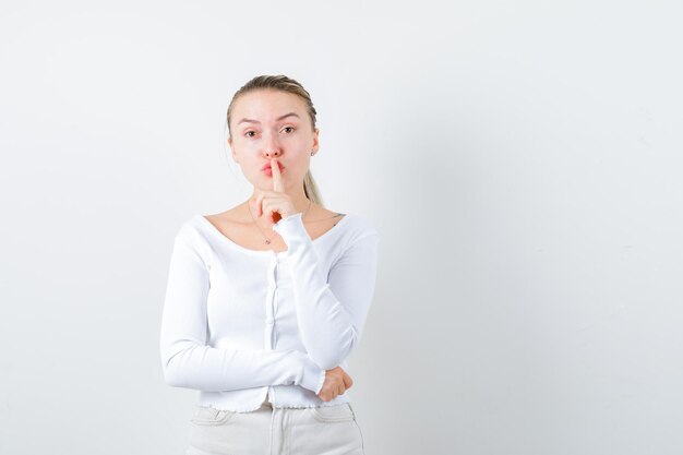 Blonde woman is showing to keep silent on white background