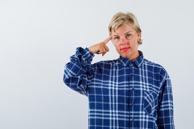 The blonde woman is thinking by holding her forefinger on temple on white background