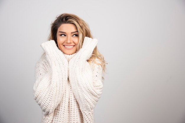 Blonde woman in knitted sweater smiling happily. 