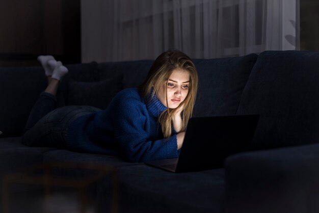 Blonde woman laying on couch with laptop