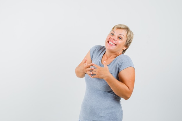 Blonde woman in light blue t-shirt inviting to come and looking serious , front view.