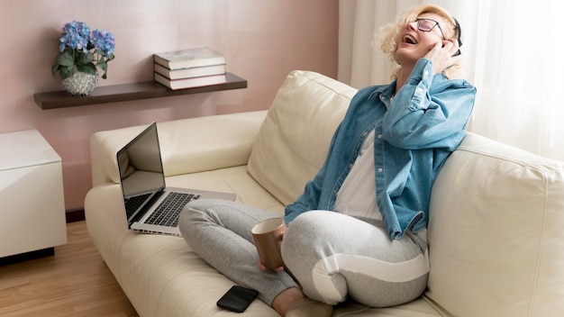 Free Photo blonde woman listening to music and holding coffee mug