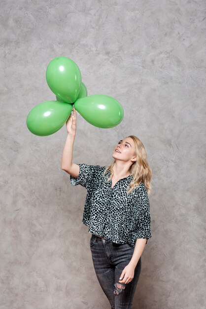 Blonde woman looking at green balloons