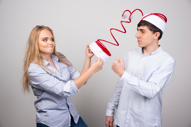 Blonde woman model giving Christmas swirl hat to guy model