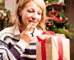 Free photo blonde woman opening christmas gifts
