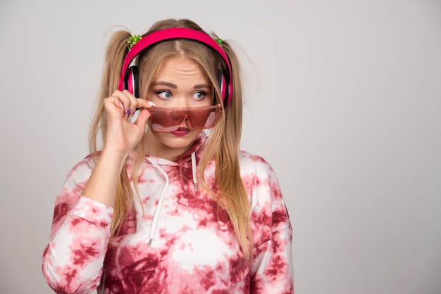 Blonde woman in pink glasses looking at her side.