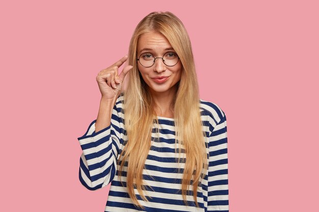 blonde woman posing against the pink wall