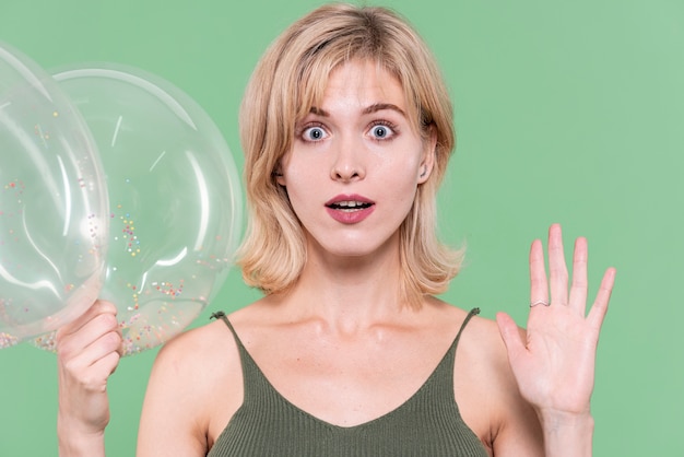 Blonde woman posing shocked and holding balloons