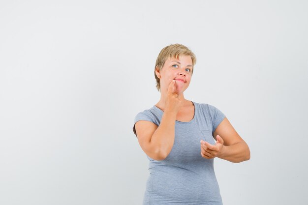 Blonde woman pretending to look at phone and thinking about something in light blue t-shirt and looking pensive. front view.